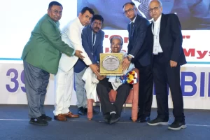 Dr. Venkataram Mysore being honoured with the Amar Kanth Jha Oration plaque at the IADVL Bihar CUTICON 2025 on stage in Puri